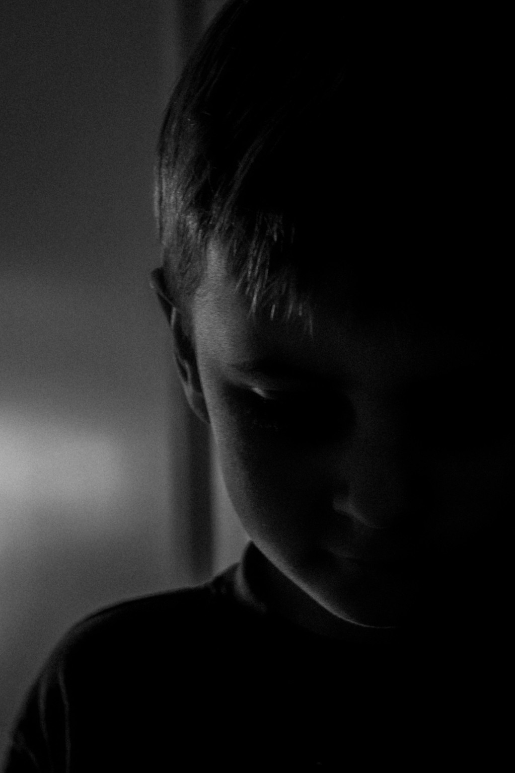 Zwart-witportret van een jongen met zijn gezicht half in de schaduw